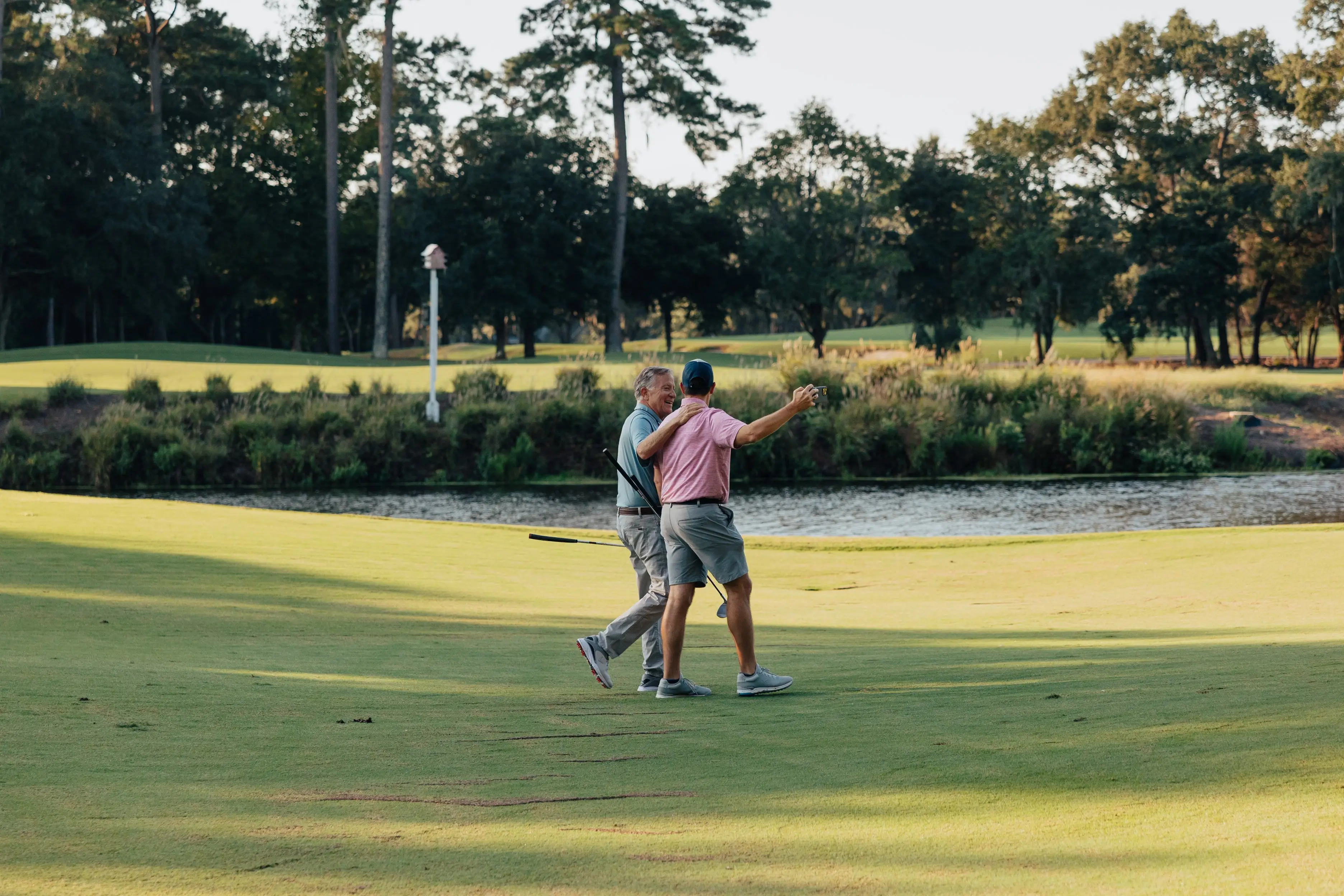 Two golfers walking a fairway together at sunset
