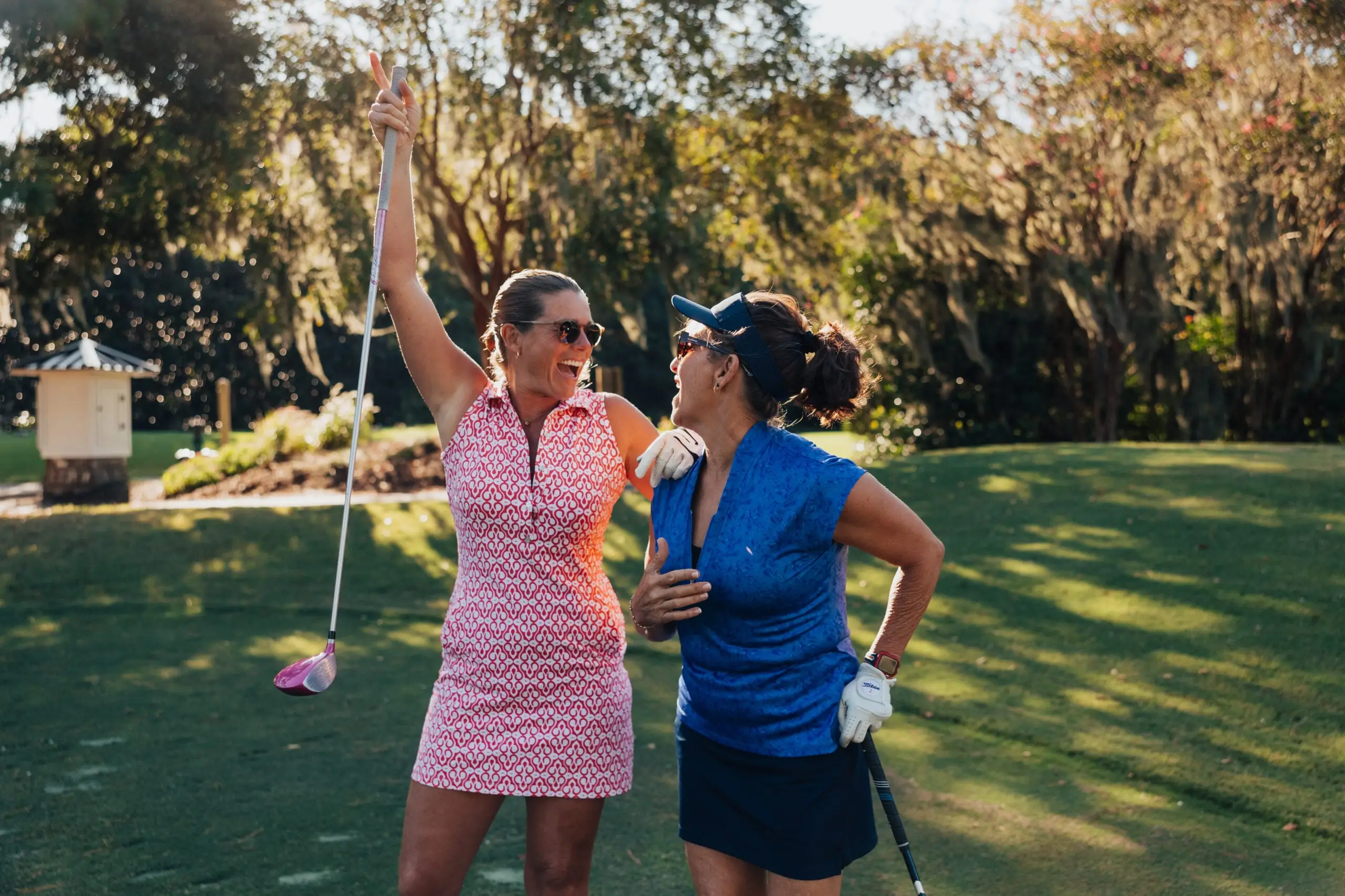 Two golfers laughing together after a drive off the tee