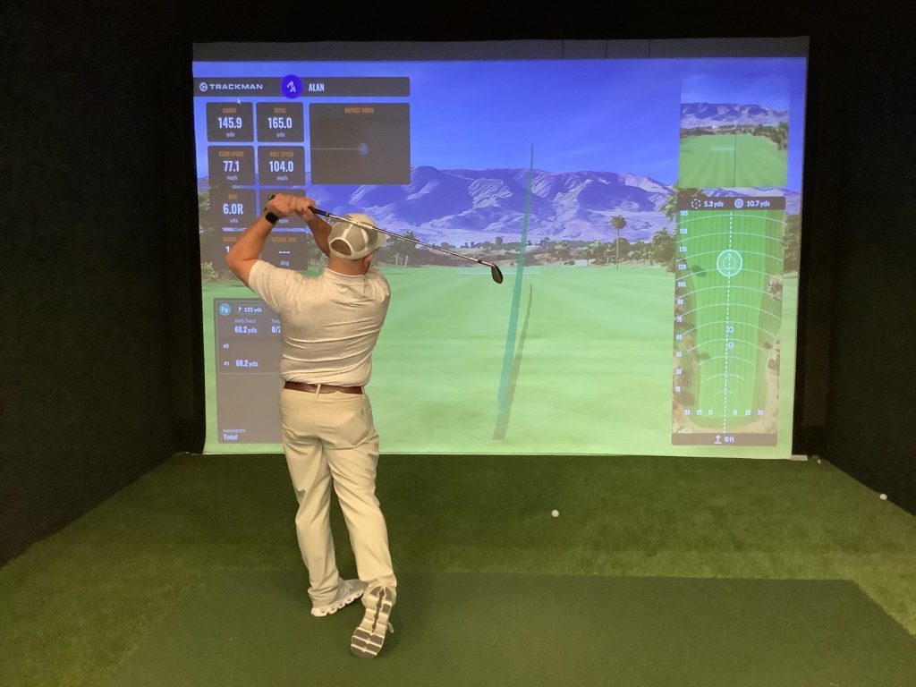 A golfer hitting into a Trackman simulator bay at Pin Point Indoor Pickleball and Golf in Little River