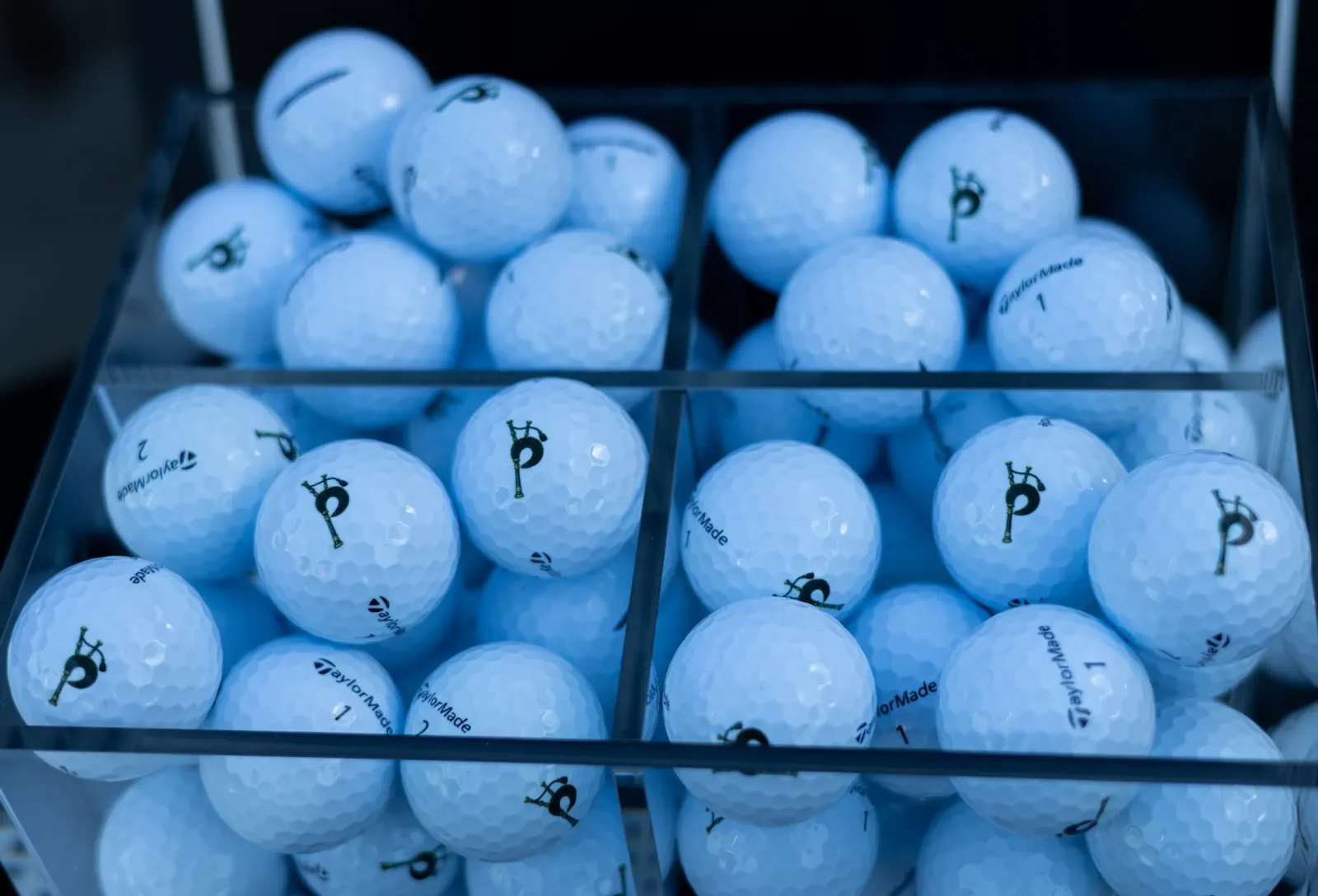 A tray of white range balls each printed with The Piper bagpipe logo