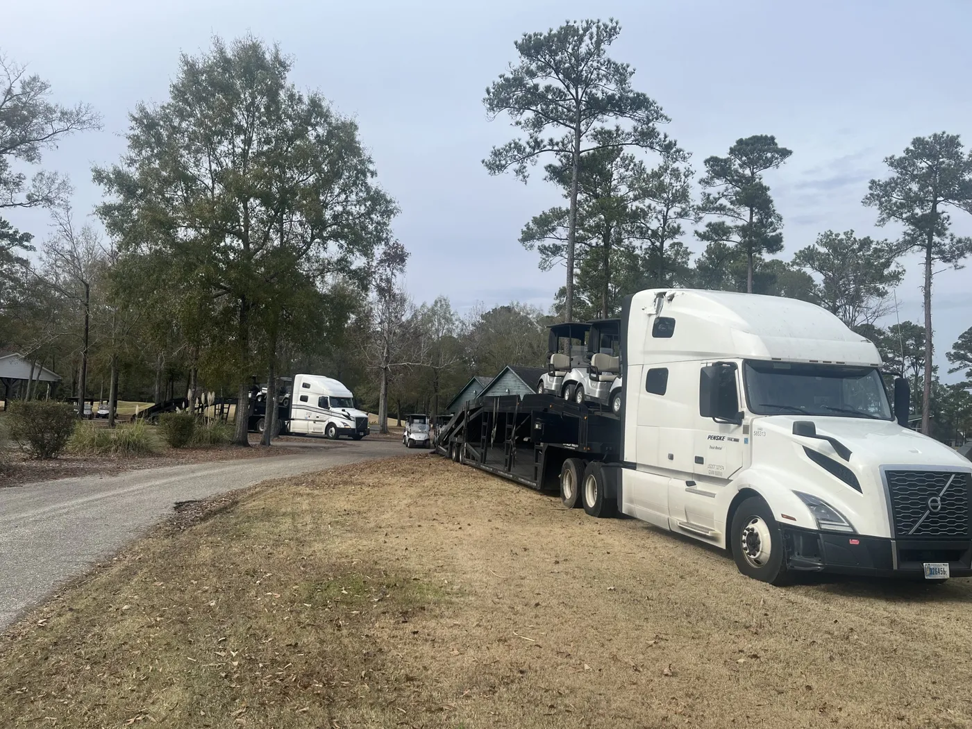 A fleet of golf carts being loaded onto a flatbed truck outside the River Oaks clubhouse